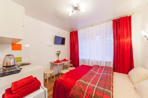 クラスノダールにあるСтудии на Бургасской K8rentのベッドルーム1室(赤いベッド1台付)、キッチンが備わります。