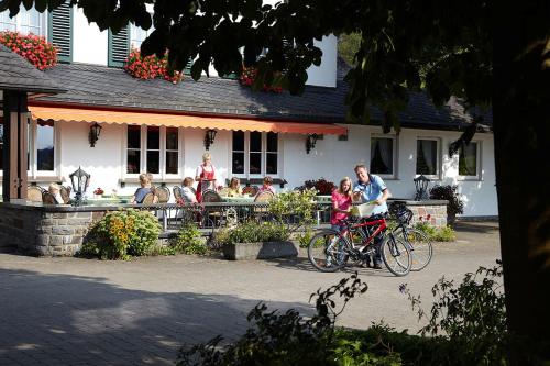 a man and a child on a bike in front of a building at Landhotel Halbfas-Alterauge in Drolshagen