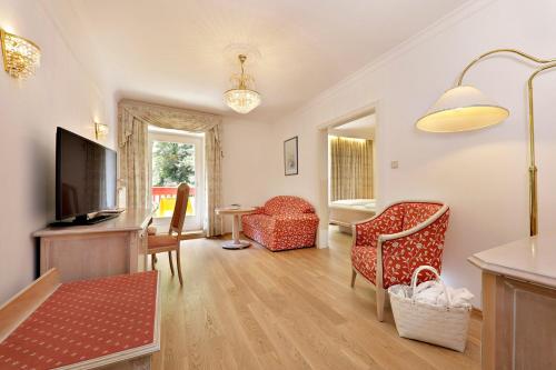 a living room with a flat screen tv and chairs at Hotel Mühle Mayer in Termeno