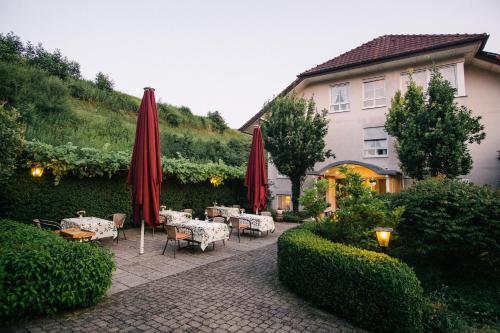 a patio with tables and red umbrellas and a building at Landhaus Keller - Hotel & Restaurant in Malterdingen