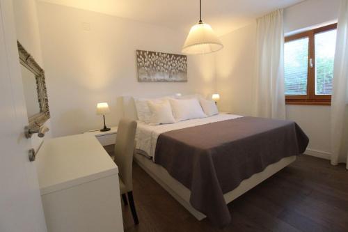 a bedroom with a bed and a desk and a window at Vila Nainer in Pag