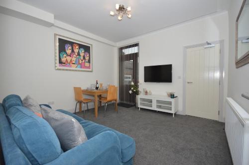 a living room with a blue couch and a table at Lexicon House - 4 bedrooms 3 bathrooms in Stoke on Trent