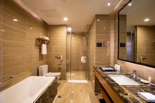 a bathroom with a tub and a sink and a toilet at Zhangjiajie Huatian Hotel in Zhangjiajie
