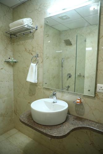 a bathroom with a sink and a mirror at Lemon Green Inn in New Delhi