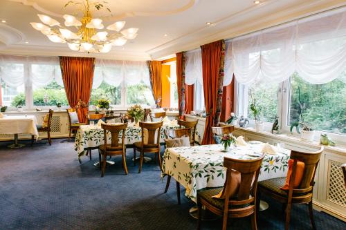 a dining room with tables and chairs and windows at Landhaus Keller - Hotel & Restaurant in Malterdingen