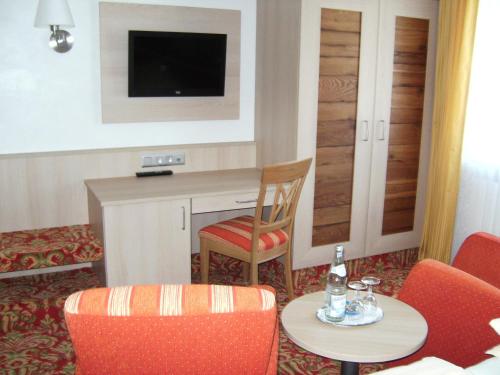 a hotel room with a table and chairs and a television at Landhotel Halbfas-Alterauge in Drolshagen