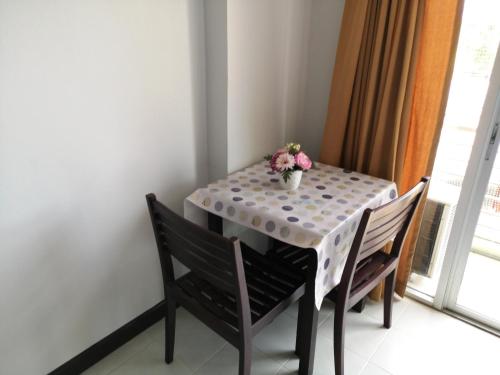 a table with two chairs and a vase of flowers on it at Sirapa Resident in Chachoengsao