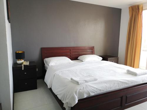 1 dormitorio con 1 cama grande con sábanas y almohadas blancas en Sirapa Resident, en Chachoengsao