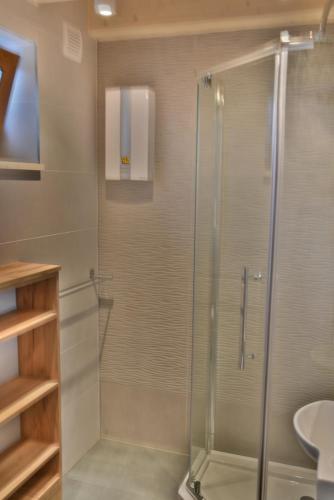 a glass shower in a bathroom with a sink at Domek - Apartament Marynarski z Kominkiem in Ustka