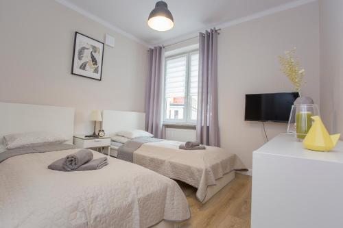 Cette chambre comprend deux lits et une télévision. dans l'établissement CR Apartament przy Rynku Sienkiewicza 6, à Białystok