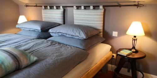 a bedroom with a bed with pillows and a lamp at La Normandise in Cormeilles