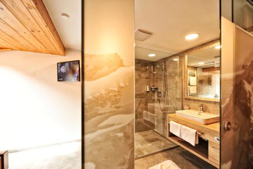 two images of a bathroom with a sink and a shower at Alpenhof Pitztal in Sankt Leonhard im Pitztal