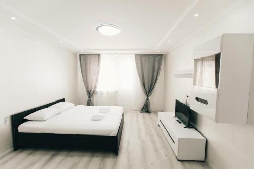 a white bedroom with a bed and a television at Rika apartments in Chernivtsi