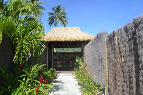 a garden entrance to a house with a thatched roof at Serenity Villas Rarotonga in Rarotonga