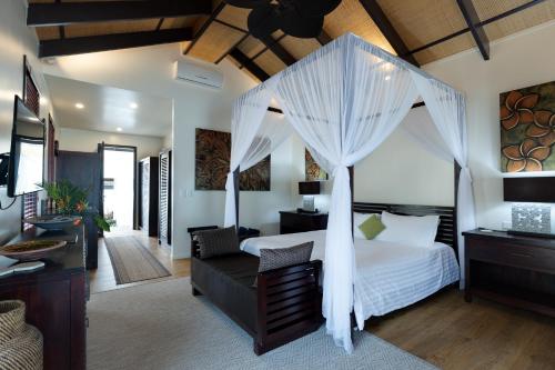 1 dormitorio con 1 cama con dosel en Serenity Villas Rarotonga, en Rarotonga