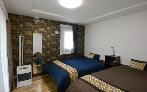 a bedroom with two beds and a window at KIYAZA Home Sapporo in Sapporo