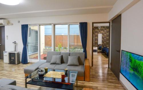 a living room with a couch and a tv at KIYAZA Home Sapporo in Sapporo