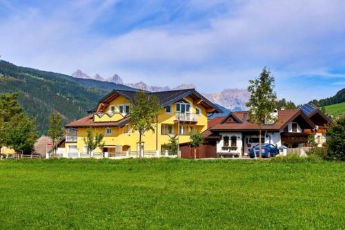a large yellow house in a field of green grass at Appartement Königslehen in Radstadt