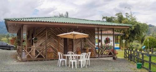 a building with a table and chairs and an umbrella at Hotel Bariloche in Santa Rosa de Cabal