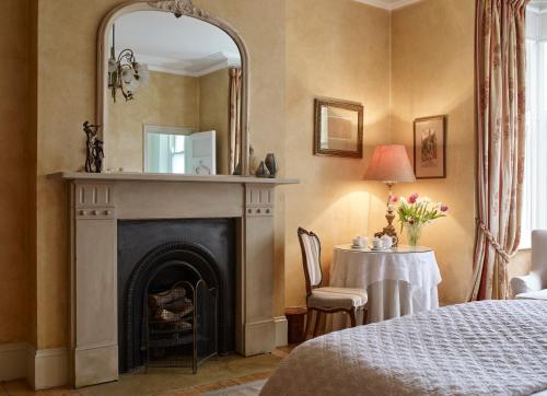 a bedroom with a fireplace with a mirror and a table at Mountview Guesthouse Crouch End in London