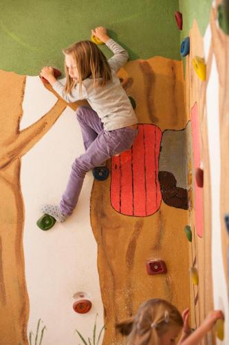 a little girl is climbing on a climbing wall at Hotel Gasteigerhof in Neustift im Stubaital