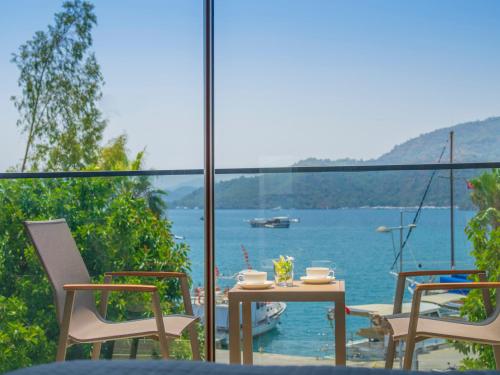 a table and chairs on a balcony with a view of the water at Hotel Marina Bay Göcek in Göcek