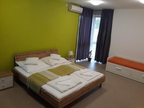 1 dormitorio con 1 cama grande y pared verde en Bella Vendégház Mórahalom en Mórahalom