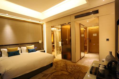 a bedroom with a large bed and a large mirror at JinJiang International Hotel Urumqi in Ürümqi