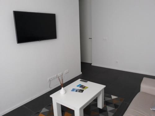 a living room with a white table and a tv at Angra Downtown in Angra do Heroísmo