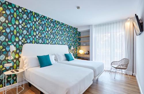 a bedroom with two beds and a wall with a mural at Hotel Anabel in Lloret de Mar