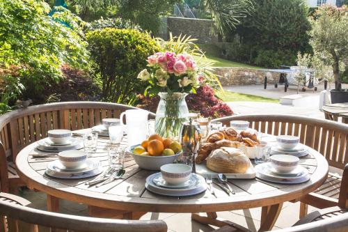 a table with a bowl of bread and a vase of flowers at Merchants House in Salcombe