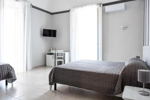 a bedroom with a bed and a tv on the wall at Hotel Costanza in Catania
