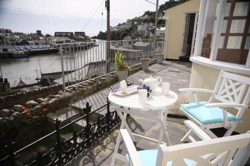 a patio with a table and chairs on a balcony at Polmear Harbour View With Terrace in Looe