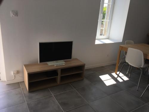 sala de estar con TV de pantalla plana sobre una mesa en TANTE LICHE, en Penmarch