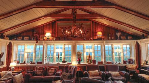 a living room with chairs and a chandelier and windows at Skarvruets Högfjällshotell in Tänndalen