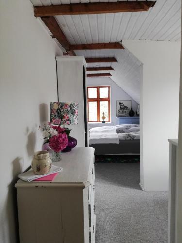 Una habitación con una cama y una mesa con flores. en Tankefuld Living's Horsefarm en Svendborg