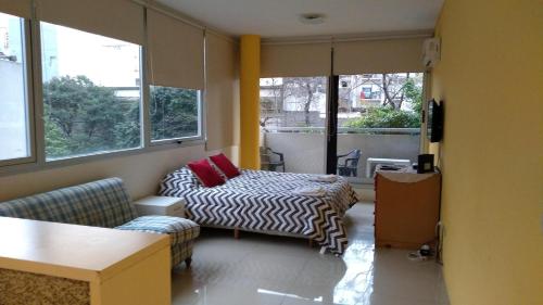 Una habitación con una cama y un sofá y ventanas. en SOLAR DEL ABASTO, en Buenos Aires