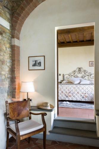 a bedroom with a bed and a chair and a lamp at Fattoria Pogni in Marcialla