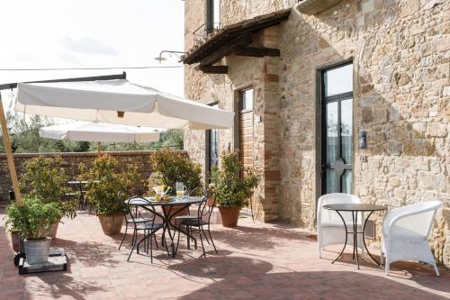 a patio with tables and chairs and an umbrella at Fattoria Pogni in Marcialla