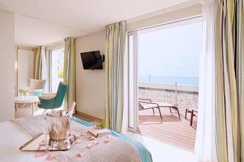a room with a room with a view of the beach at Hôtel de la Baie - Thalassothérapie PREVITHAL in Donville-les-Bains
