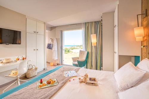 ドンヴィル・レ・バンにあるHôtel de la Baie - Thalassothérapie PREVITHALの海の景色を望むベッド付きのホテルルームです。