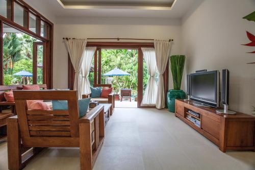 a living room with a tv and a couch at Baan Pinya Balinese Style Pool Villa in Krabi town