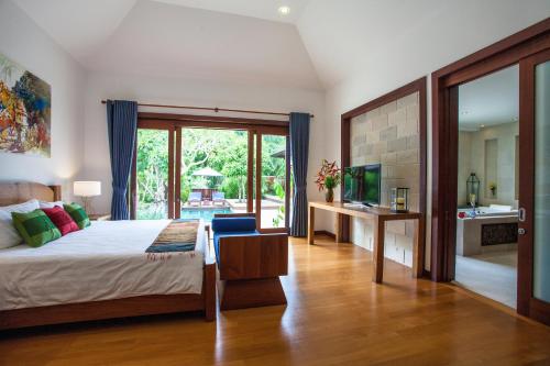 a bedroom with a bed and a television and a bathroom at Baan Pinya Balinese Style Pool Villa in Krabi town