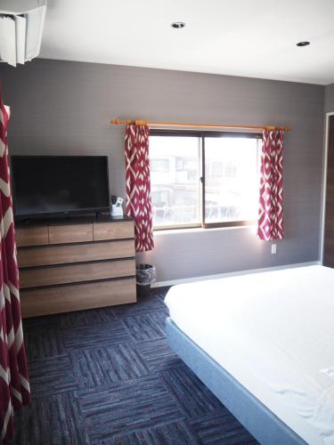 a bedroom with a bed and a tv and a window at GUEST HOUSE BOSTONS in Niigata