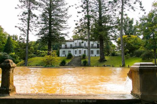 a large house is surrounded by a pool of water at Apartamento Lombinha in Vila Franca do Campo