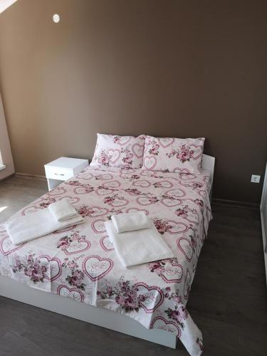 a bedroom with a pink bed with two towels on it at Complex Karia I in Kavarna