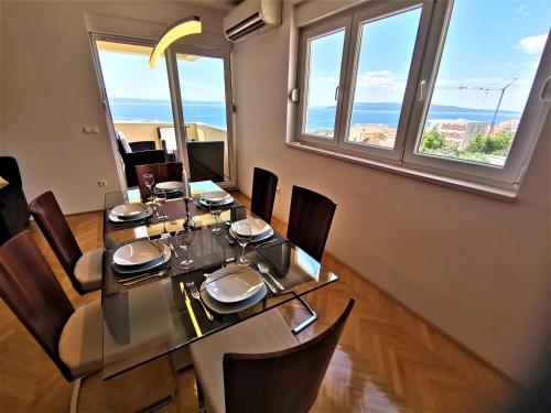 ein Esszimmer mit einem Tisch, Stühlen und Fenstern in der Unterkunft Apartment Makarska, panoramic sea & mountains view, Čuček in Makarska