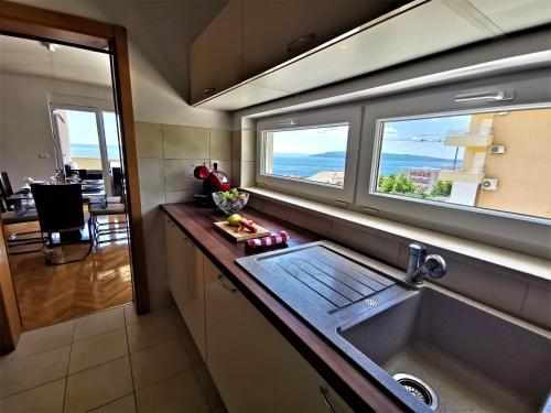 eine Küche mit einem Waschbecken und einem großen Fenster in der Unterkunft Apartment Makarska, panoramic sea & mountains view, Čuček in Makarska