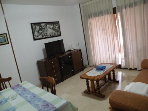 a living room with a table and a tv at Los Pinos - Fincas Arena in Benidorm