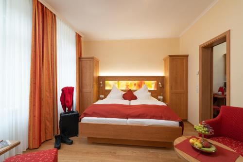 a hotel room with a bed and a red chair at Altkölnischer Hof in Bacharach